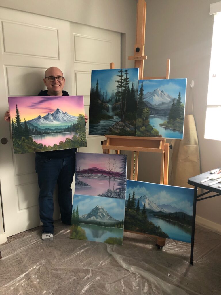 Daniel showing off five of his paintings inspired by Bob Ross