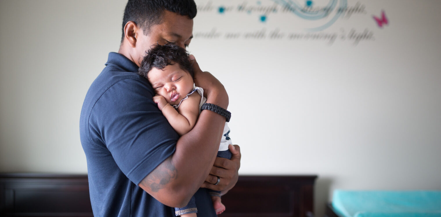 Father cradling his new born baby in his arms.