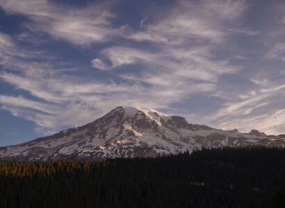 Snowcapped mountain with a foothill of evergreens