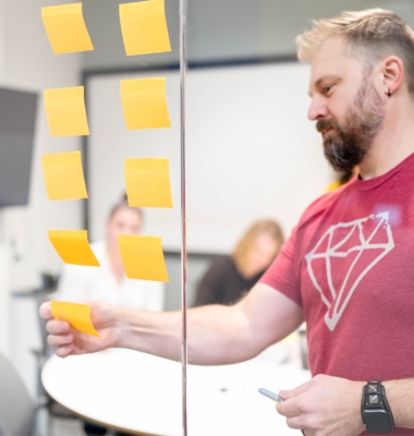 Kirk Solar adding post-it notes to the wall during a collaboration meeting.