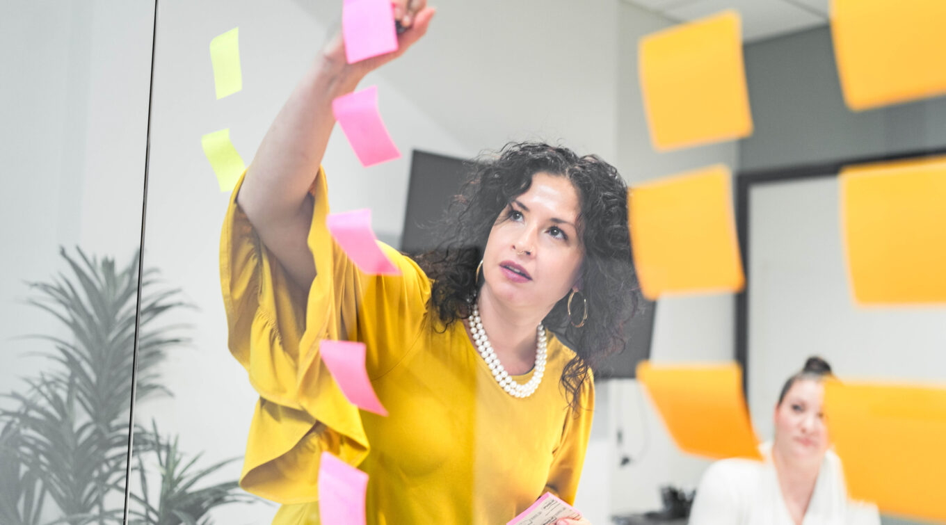 Jen Rittenhouse notating a post-it note in a strategy session in a conference room.