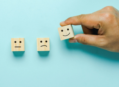 A hand holding three small boxes with faces on them.