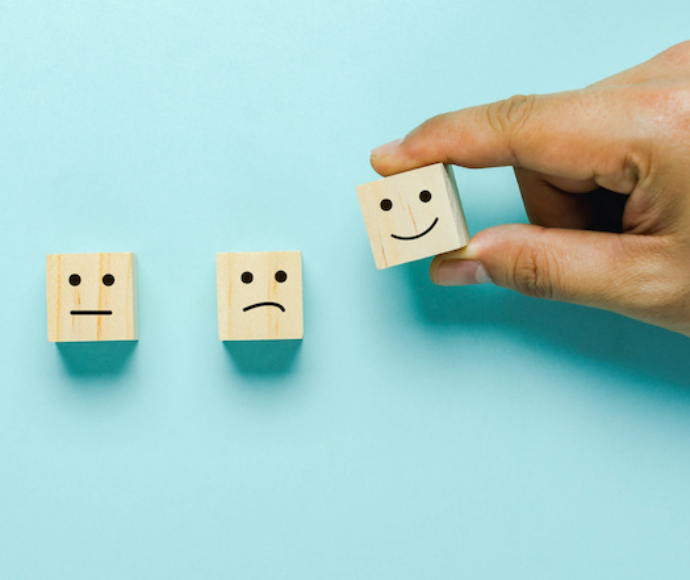 A hand holding three small boxes with faces on them.