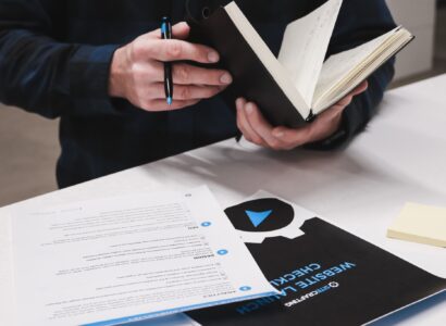 Man holding a notebook, with a checklist on the counter in front of him.