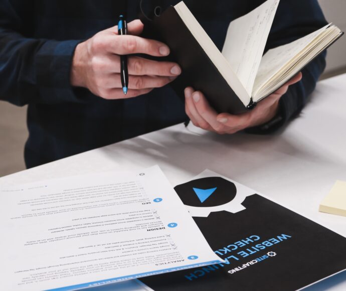 Man holding a notebook, with a checklist on the counter in front of him.